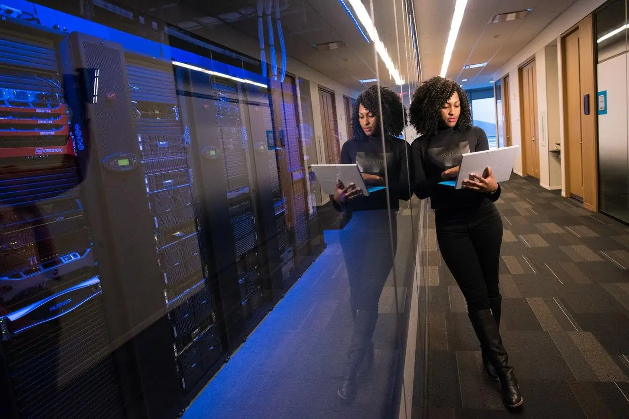 Racked Server background with Engineer holding a Laptop